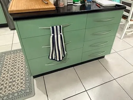 Kitchen island before resurfacing, with green drawers and a black benchtop